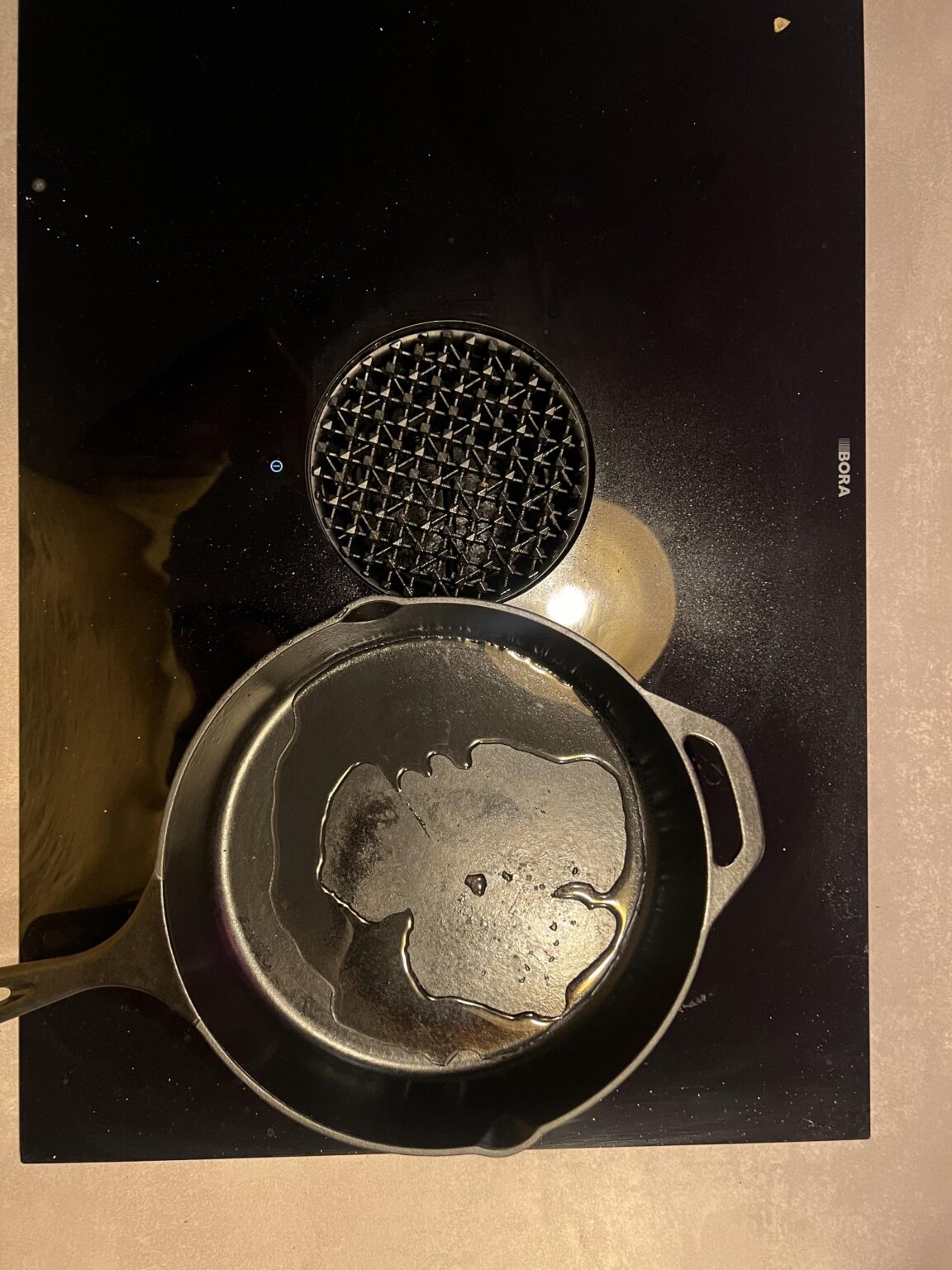 Öl läuft in der gusseisernen Pfanne an den Rand Öl läuft in der gusseisernen Pfanne an den Rand