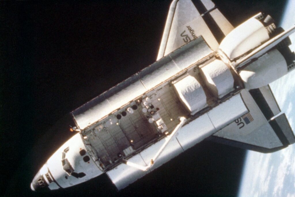 Ein Overhead-Blick auf den Space Shuttle Challenger, der von einer festen Kamera aufgenommen wurde, die während der ersten Extravehikularaktivität (EVA) mit der stickstoffgesteuerten, handgesteuerten, bemannten Manövereinheit (MMU) auf dem Helm von Astronaut Bruce McCandless (EVA) aufgenommen wurde. Februar 1984 Ein Overhead-Blick auf den Space Shuttle Challenger, der von einer festen Kamera aufgenommen wurde, die während der ersten Extravehikularaktivität (EVA) mit der stickstoffgesteuerten, handgesteuerten, bemannten Manövereinheit (MMU) auf dem Helm von Astronaut Bruce McCandless (EVA) aufgenommen wurde. Februar 1984