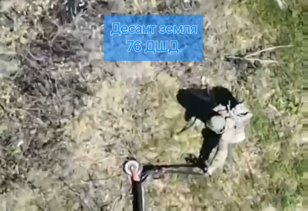 Ein russischer Fallschirmjäger versucht, seinen elektrischen Roller aus Barbewire zu entfernen, zieht ihn aber über eine Mine. (Musik von Quelle)