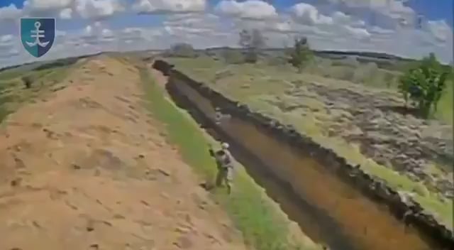 Drohnenmaterial der ukrainischen 35. Marine-Brigade zeigt einen russischen Soldaten neben einem Panzerabwehrgraben, der versucht, ein FPV-Quad mit dem Bestand seines Gewehrs zu zerstören.