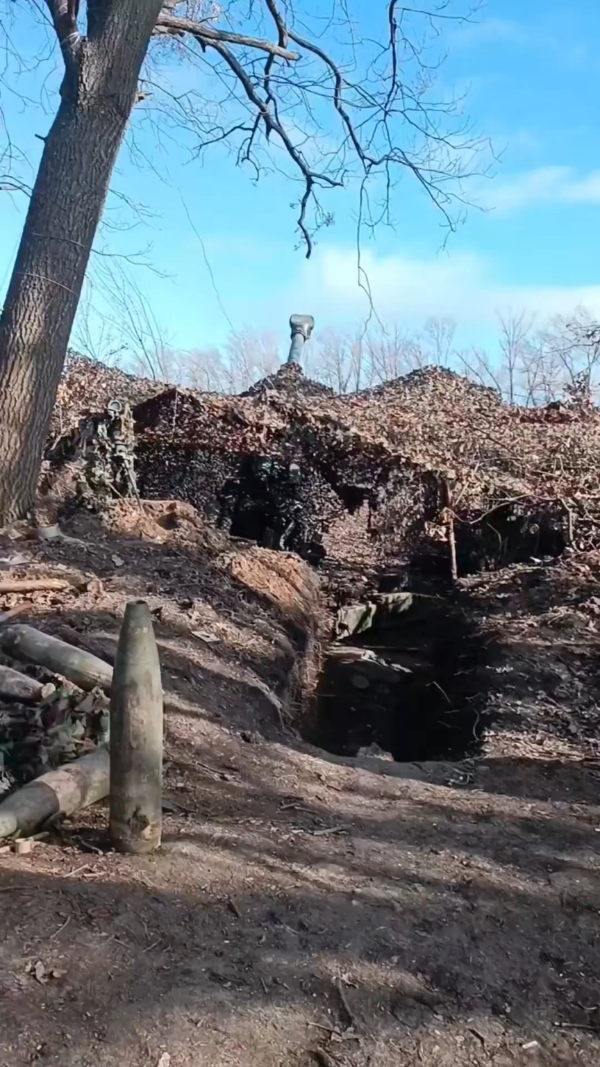 Die ukrainische Artillerie feuerte aus einem Unterstand, während ein Landwirt seinen Mähdrescher auf dem Feld direkt neben sich fährt.