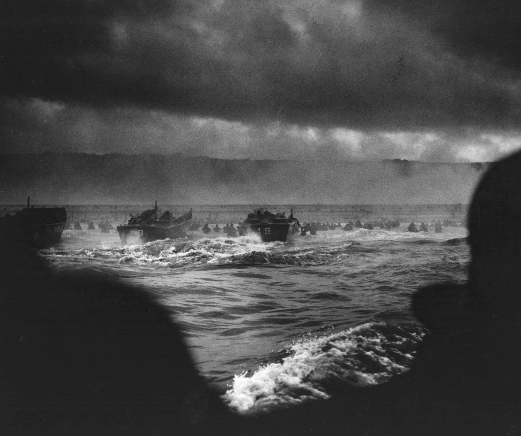 LCVP Higgins Boote nähern sich dem Sand von Omaha Beach, wo Männer unter deutschem Feuer an Land waten. 6. Juni 1944.