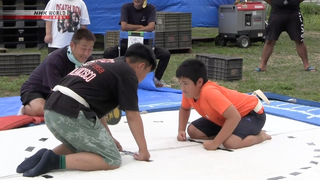 Kinder konkurrieren im knienden Sumo im Nordosten Japans