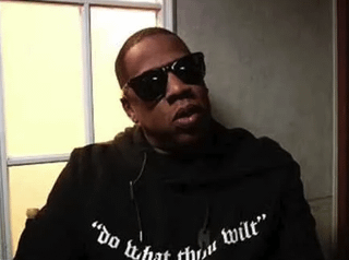 Jay Z trägt einen Alester Crowley Hoodie/Hemd, der eindeutig sagt: "Mach, was du willst."