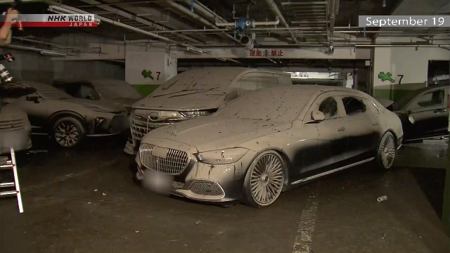 Die Besitzer überprüfen nach überflutete Autos auf dem unterirdischen Grundstück im Zentraljapan