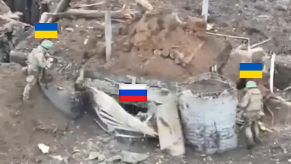 Zwei ukrainische Soldaten stehen vor einem Bunker, der von einem russischen Soldaten besetzt ist. Einer von ihnen wirft eine Sprengladung hinein. Als der russische Soldat versucht, es wieder herauszuwerfen, explodiert es.