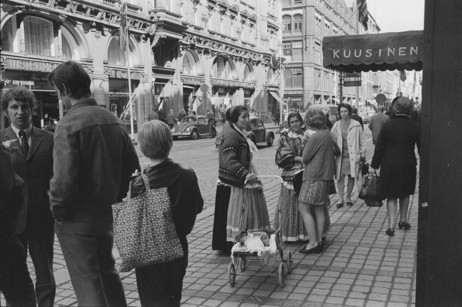 Eine Straßenszene in Helsinki mit zwei Frauen in traditioneller finnischer Grünkohl-Kleidung, gekennzeichnet durch lange, schwere Röcke und detaillierte Blusen. Die Kale sind eine finnische Roma-Gemeinschaft, deren Vorfahren aus Südasien stammten und im 16. Jahrhundert nach Finnland kamen. (1970) Eine Straßenszene in Helsinki mit zwei Frauen in traditioneller finnischer Grünkohl-Kleidung, gekennzeichnet durch lange, schwere Röcke und detaillierte Blusen. Die Kale sind eine finnische Roma-Gemeinschaft, deren Vorfahren aus Südasien stammten und im 16. Jahrhundert nach Finnland kamen. (1970)